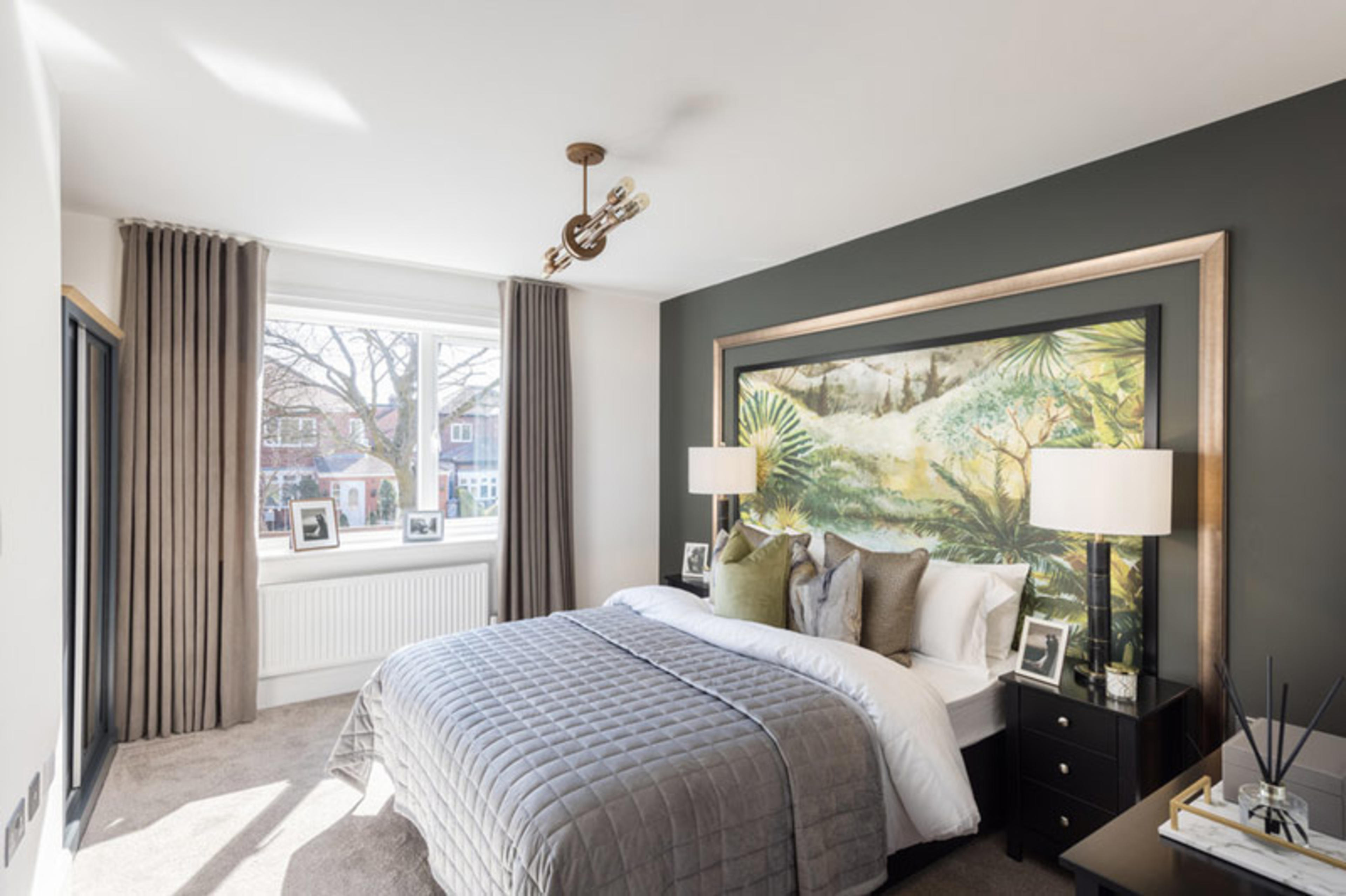 A bedroom with double bed, grey-green feature wall and bronze-coloured curtains