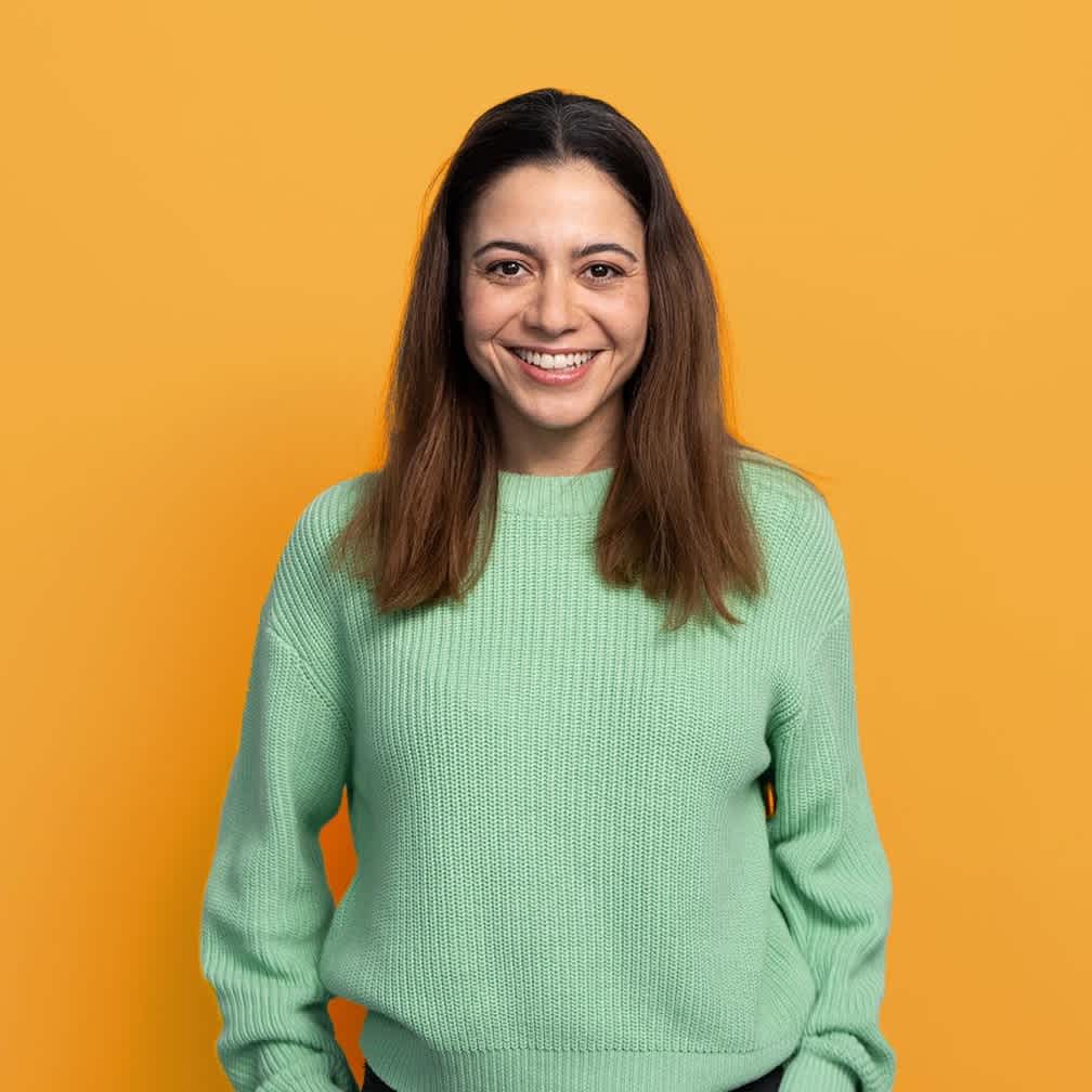 Woman smiling at camera on yellow background (top block)