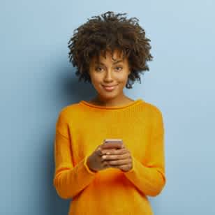 Smiling woman in yellow sweater holding a mobile phone (small card)