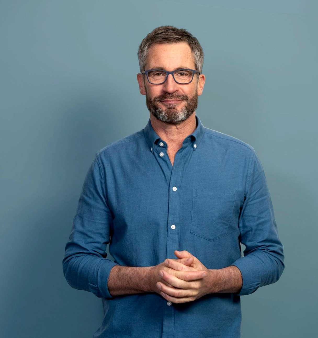 Man holding hands smiling at camera (top block)