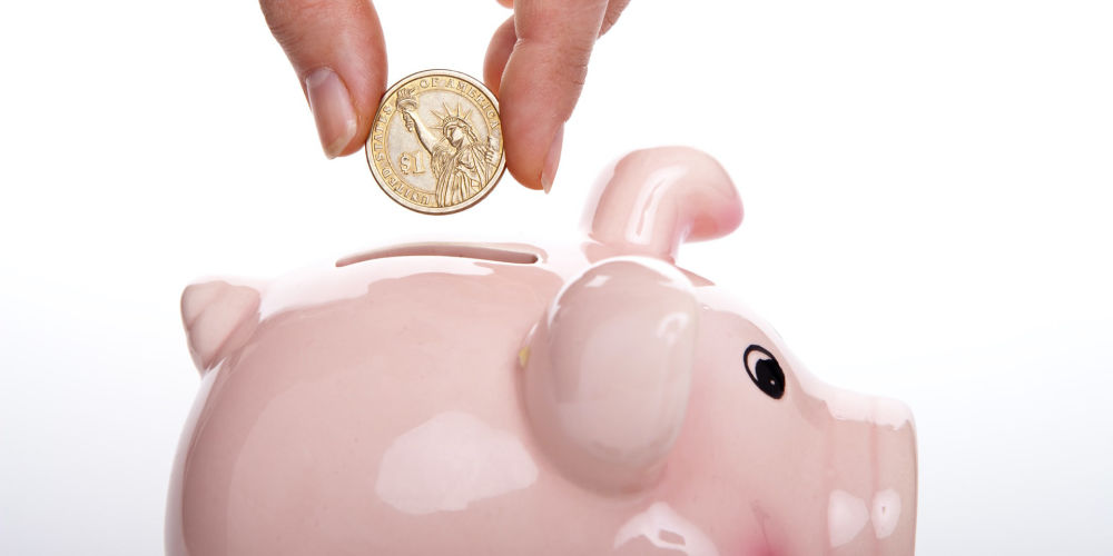 Hand dropping money into a piggy bank to symbolize funding your startup without VCs