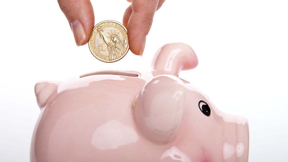 Hand dropping money into a piggy bank to symbolize funding your startup without VCs