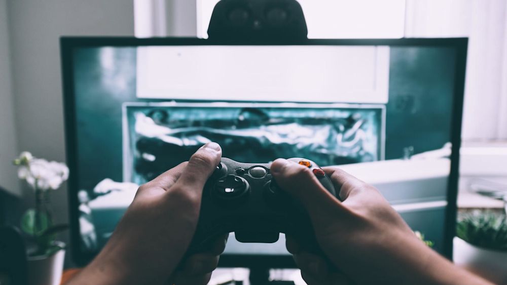 third-person view of a person holding a controller for a gaming device.