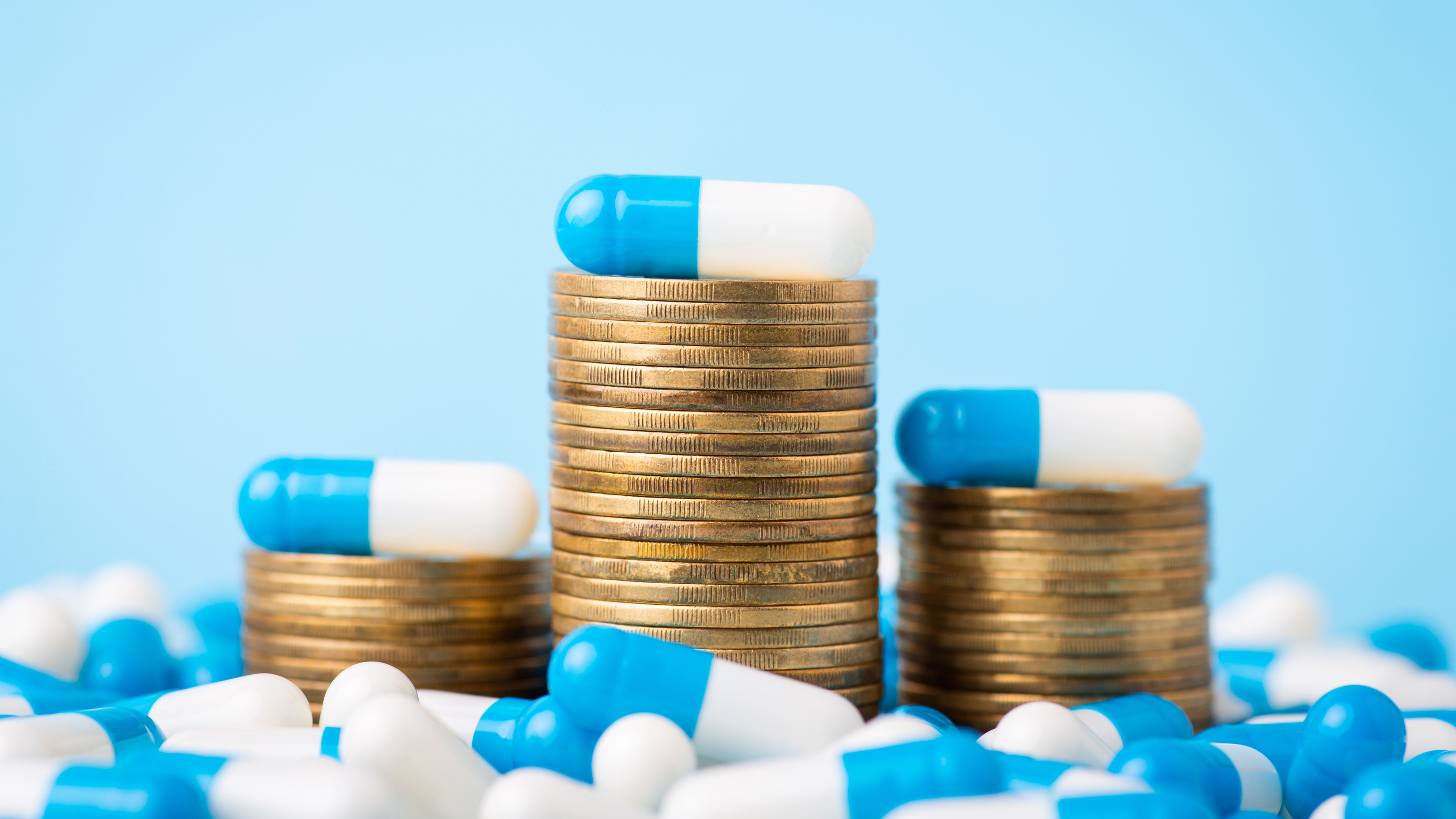 Stacks of coins between medical pills capsules. Image credit: Vitalii Petrushenko/Getty Images
