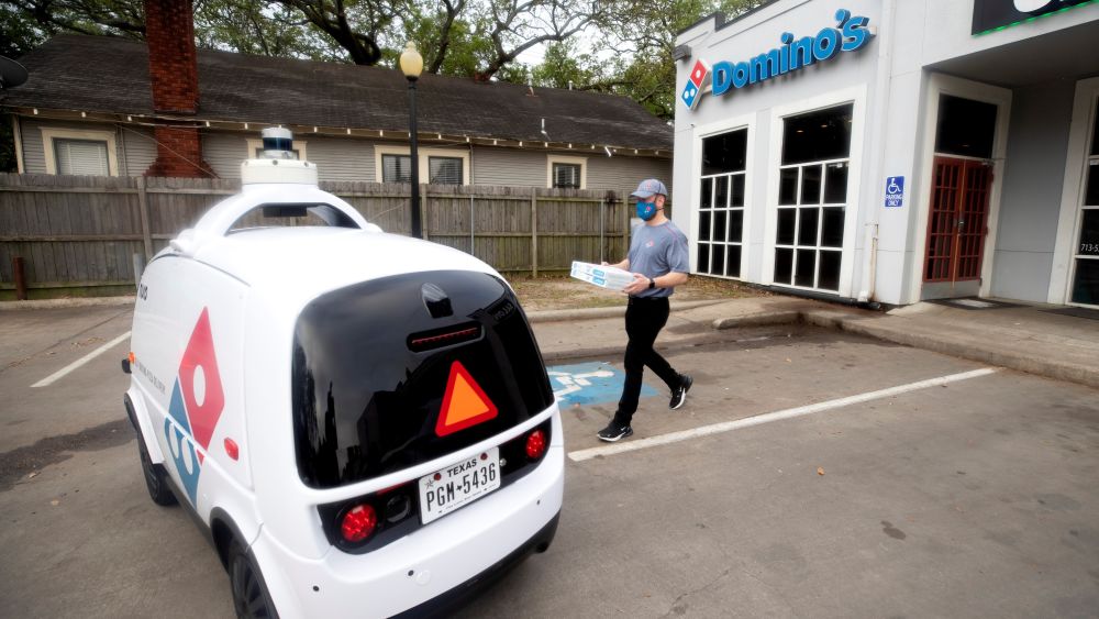 A Domino's employee places pizzas in the Nuro R2 Robot — a self-driving delivery vehicle currently operating in Houston, TX. Courtesy of Domino's.
