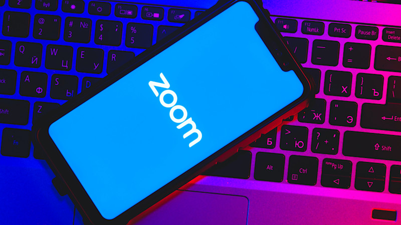Zoom logo on a phone that is lying on a laptop