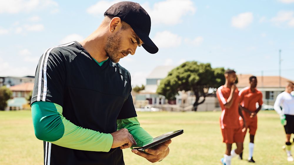 Shot of a soccer coach using a digital tablet while out on the field. Image courtesy of Katleho Seisa via Getty Images