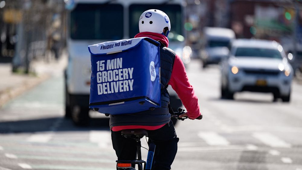 An employee rides a bike to deliver groceries from 'Fridge No More' on March 31, 2021 in the Brooklyn borough of New York City. (Photo by Angela Weiss/AFP via Getty Images)