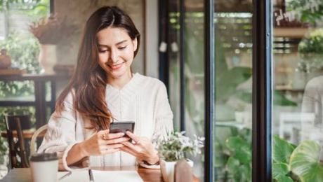 An image of a lady smiling, whilst using her phone