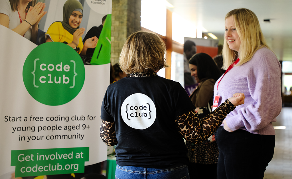 A member of the Code Club team speaks to a volunteer at an event