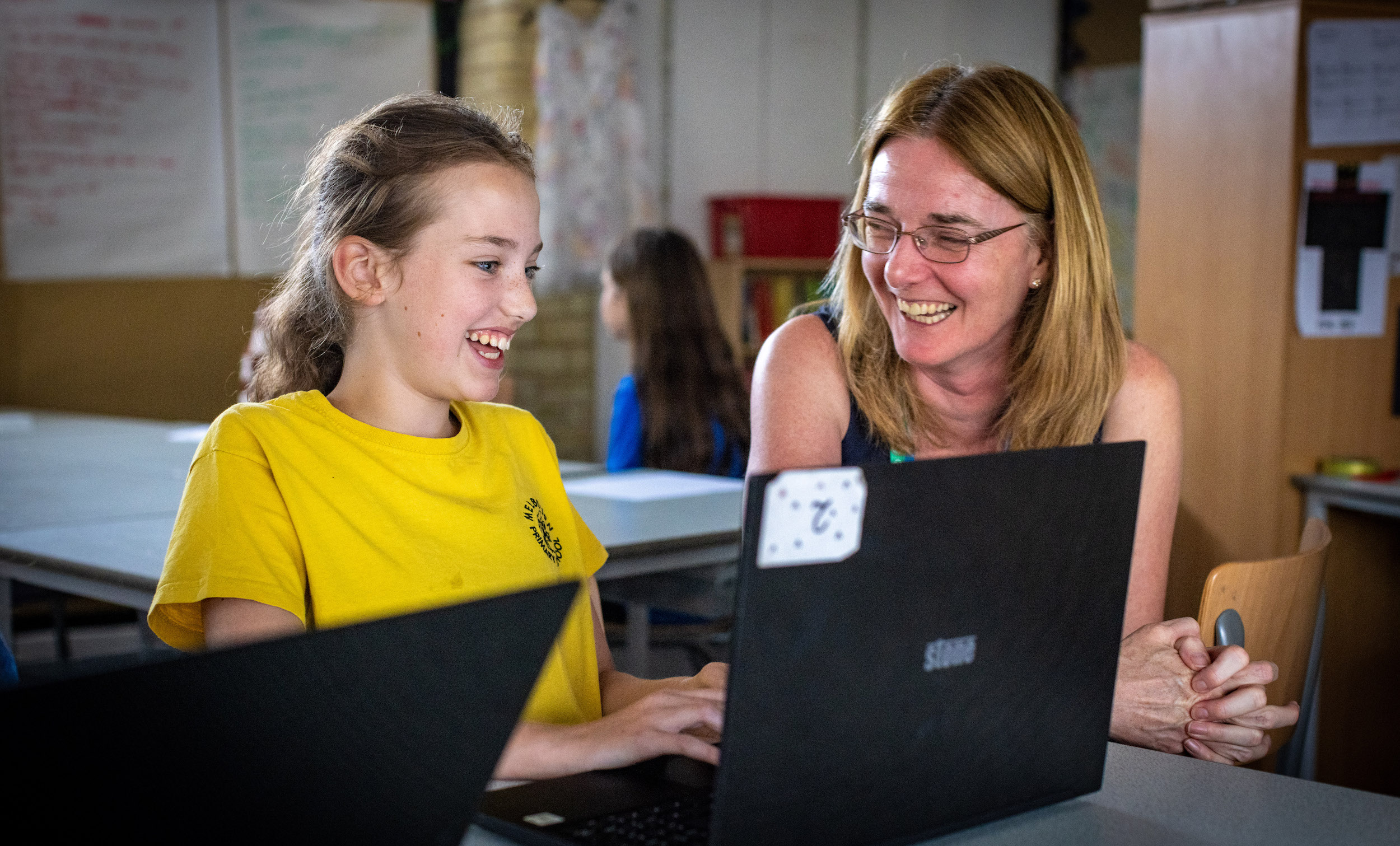 A Code Club member and volunteer code together at a laptop