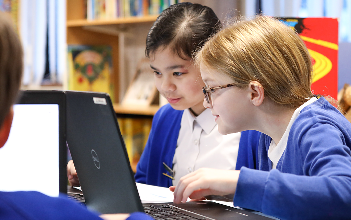 Two children work together at a laptop