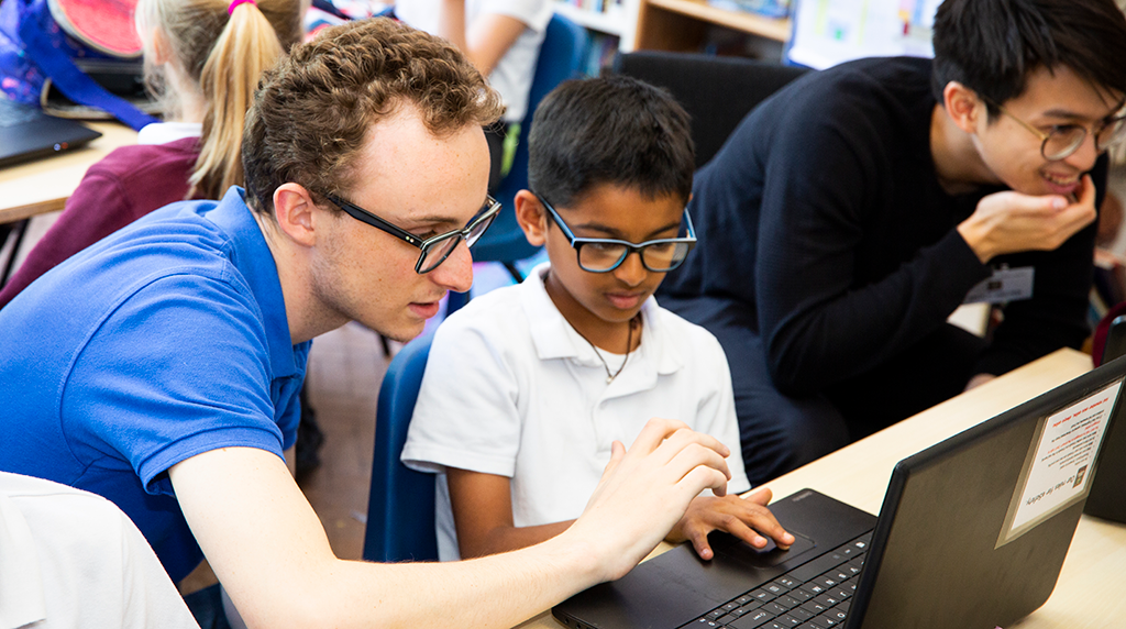 A volunteer and young person work together at a laptop