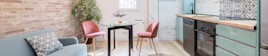 A small apartment kitchen area furnished with a table and chairs and sofa.