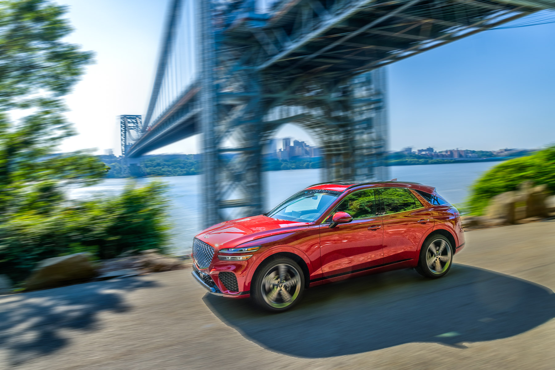 a red Genesis GV70 driving underneath a bridge