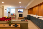 Modern basement apartment living room with modern wood wall and blue kitchen cabinets, basement window in view. 