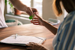 Woman accepting keys after signing rental lease agreement