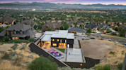 large modern black home with a backyard pool and views of Salt Lake Valley in the background. 