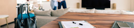 A pen and rental contract sit on a counter with a home renter and owner in the background