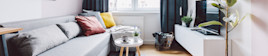 The living room of a small apartment with a couch, coffee table and television