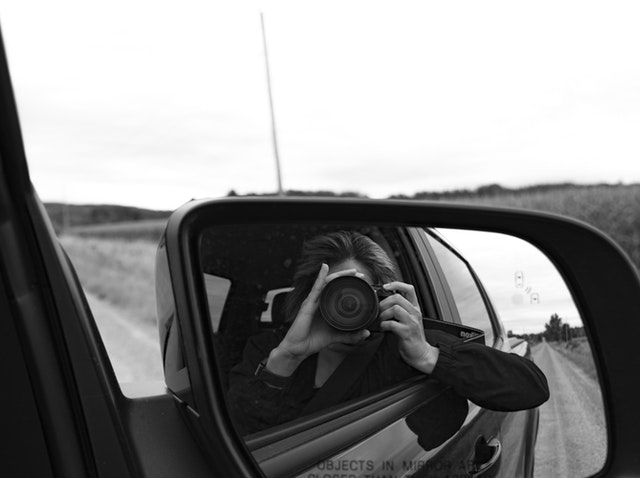 A woman taking a picture of her car.