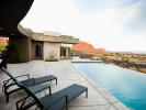 A luxurious pool in the backyard of a large home in Saint George, Utah, overlooking red rocks.