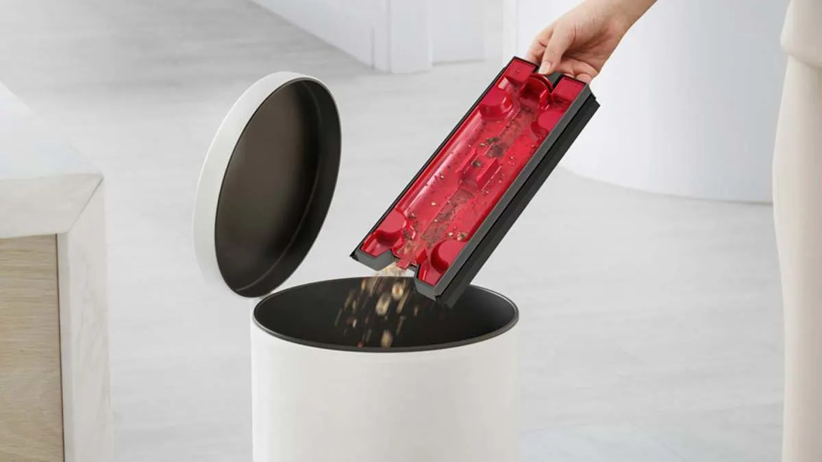 La main d’une utilisatrice vidant les débris dans une poubelle