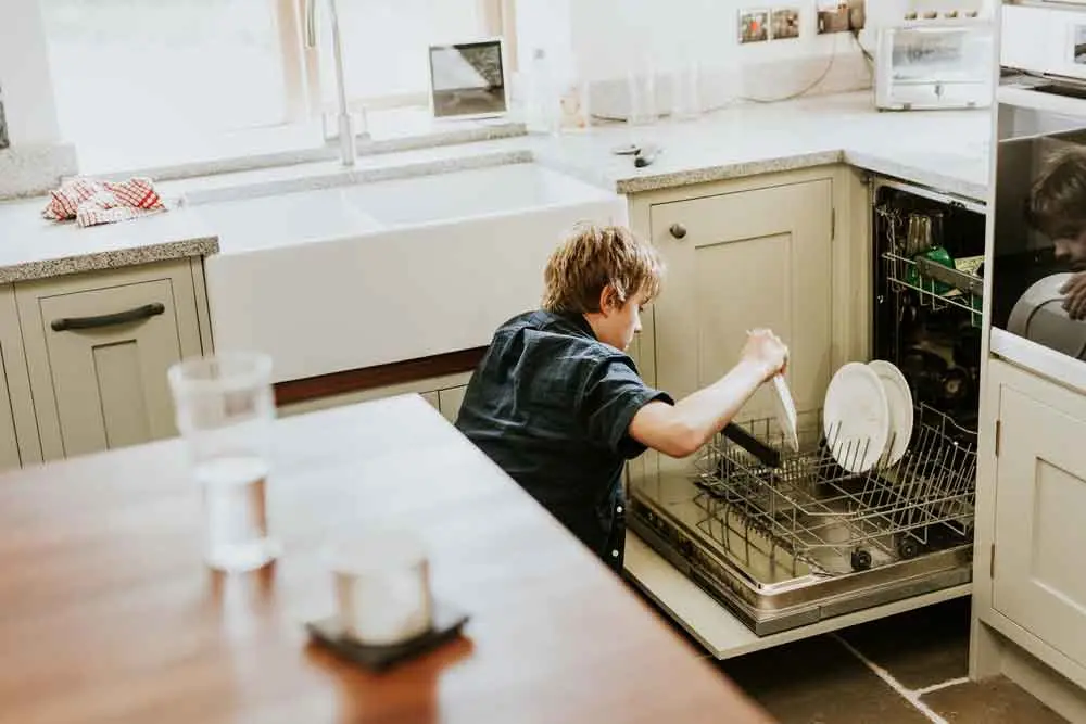 kind laadt vaatwasser in