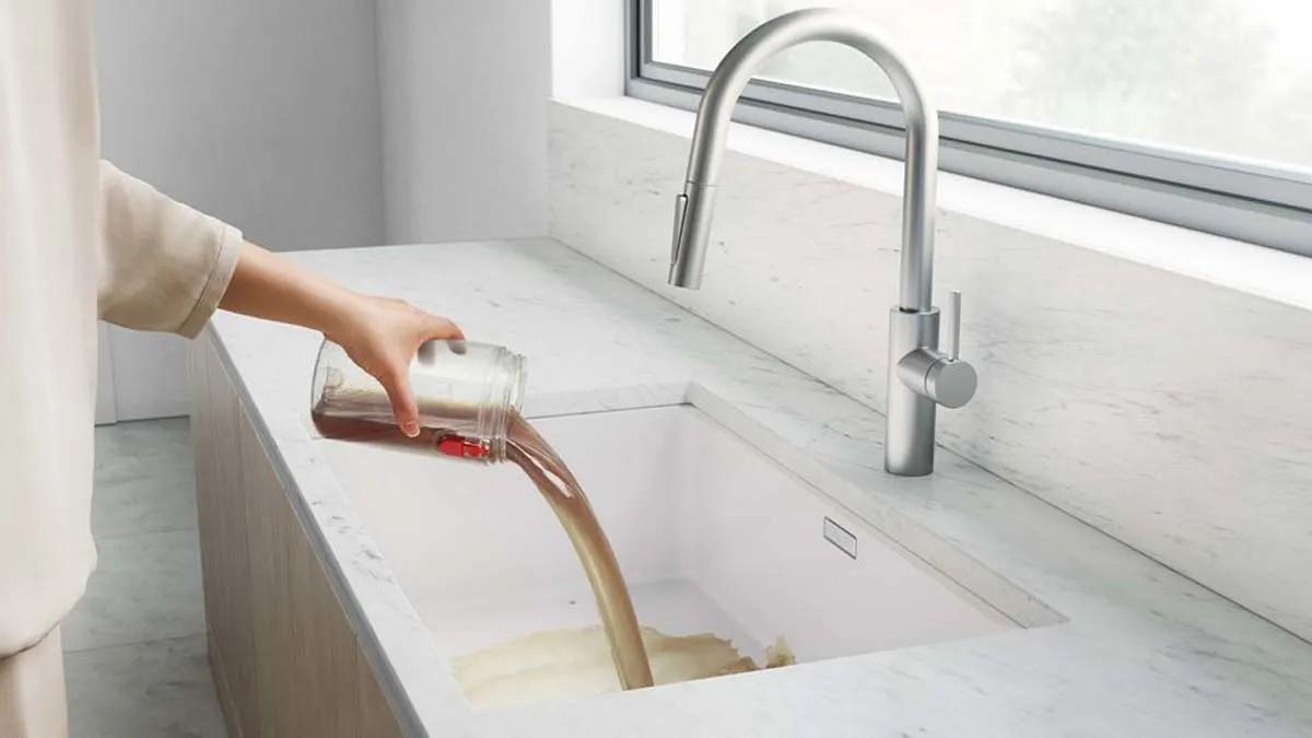 Une utilisatrice vidant le réservoir d’eau sale dans un évier