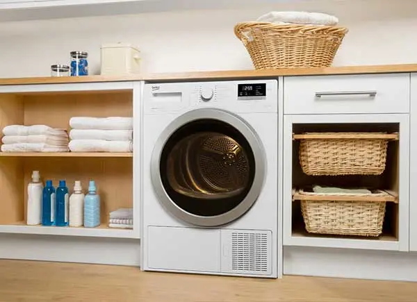 Une buanderie avec un sèche-linge et des étagères.