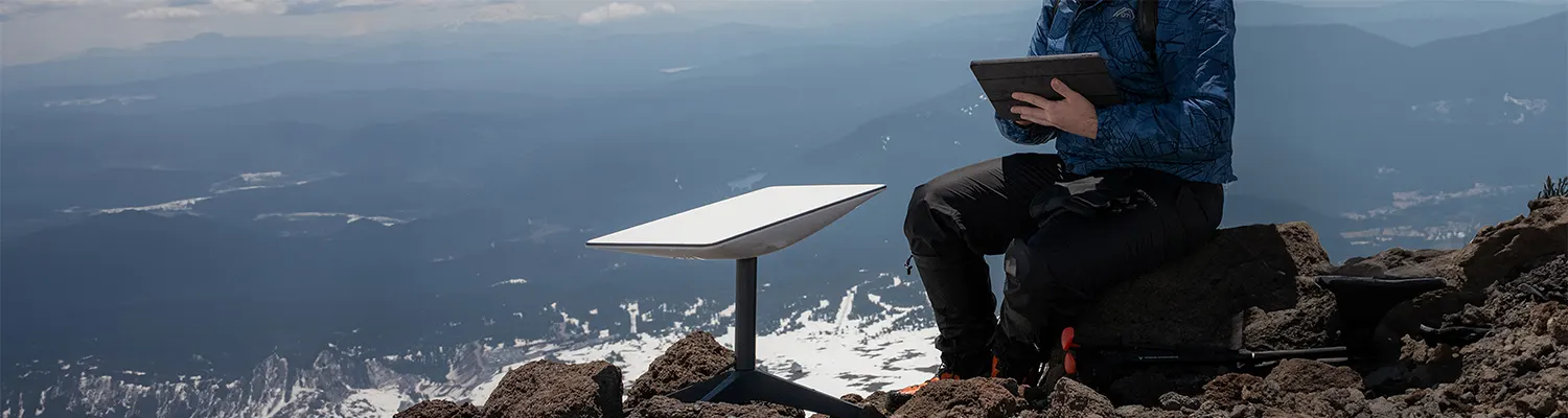 man met starlink satelliet in de bergen
