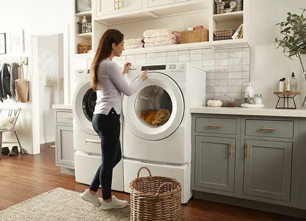 Une femme devant un lave-linge et un sèche-linge.
