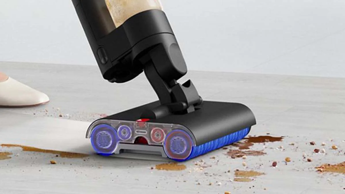 Une utilisatrice guidant le nettoyeur de sols durs Dyson WashG1 par-dessus des éclaboussures et des taches de nourriture sèches sur le sol dur d’une cuisine