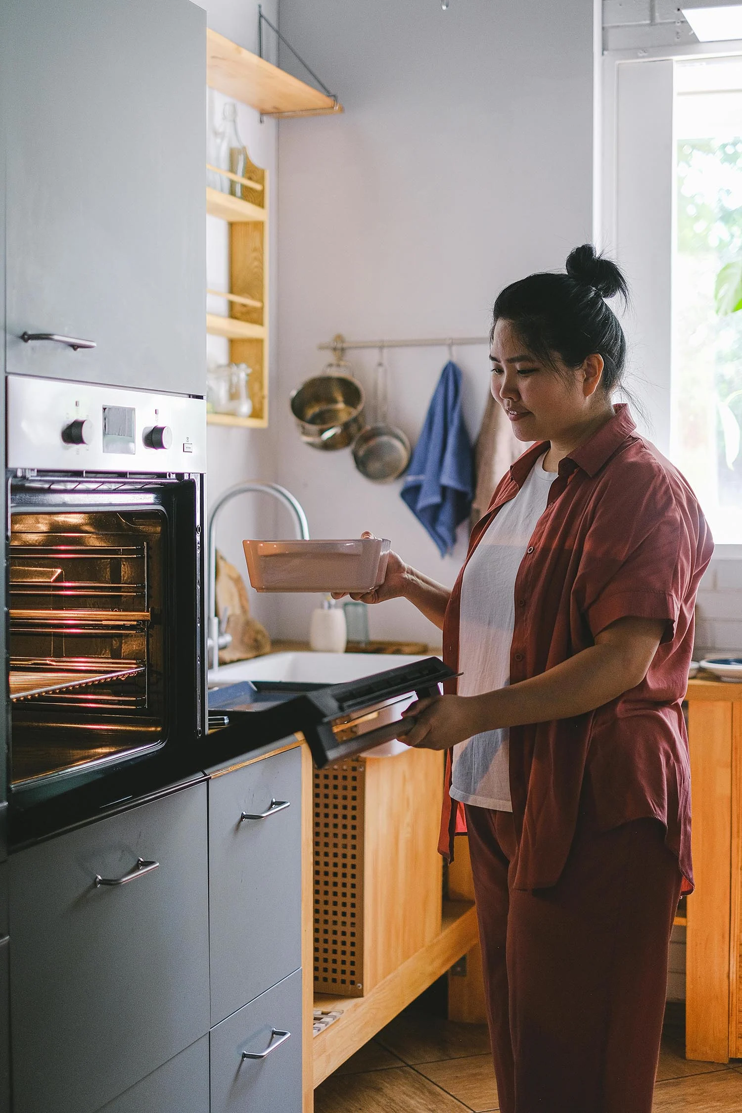 Une femme mettant un plat au four.