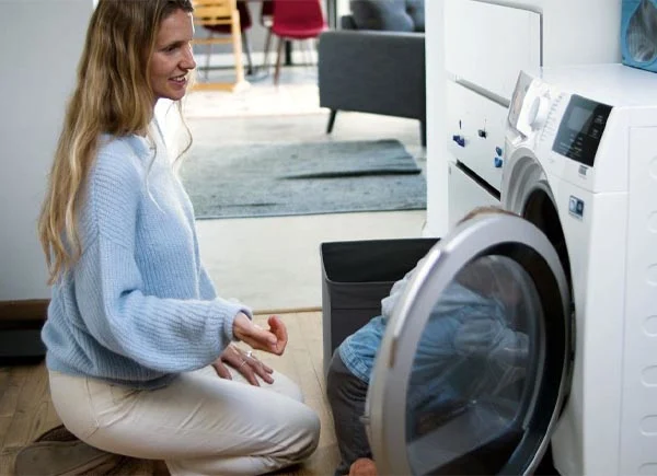 Eine Frau und ein Kind schauen sich eine Waschmaschine an.
