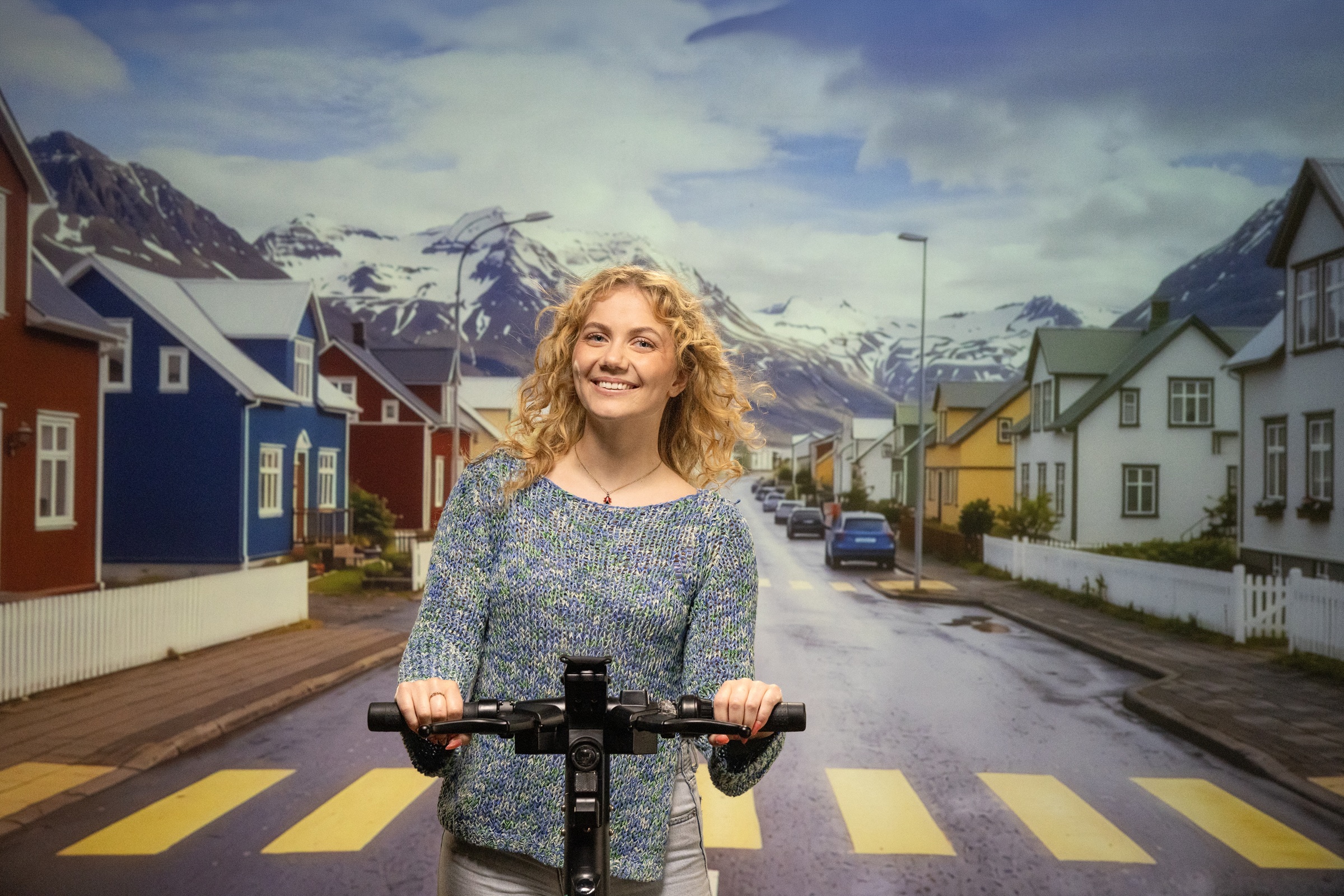 Arion framtíð - kona á hopphjóli á milli fallegra litríkra húsa