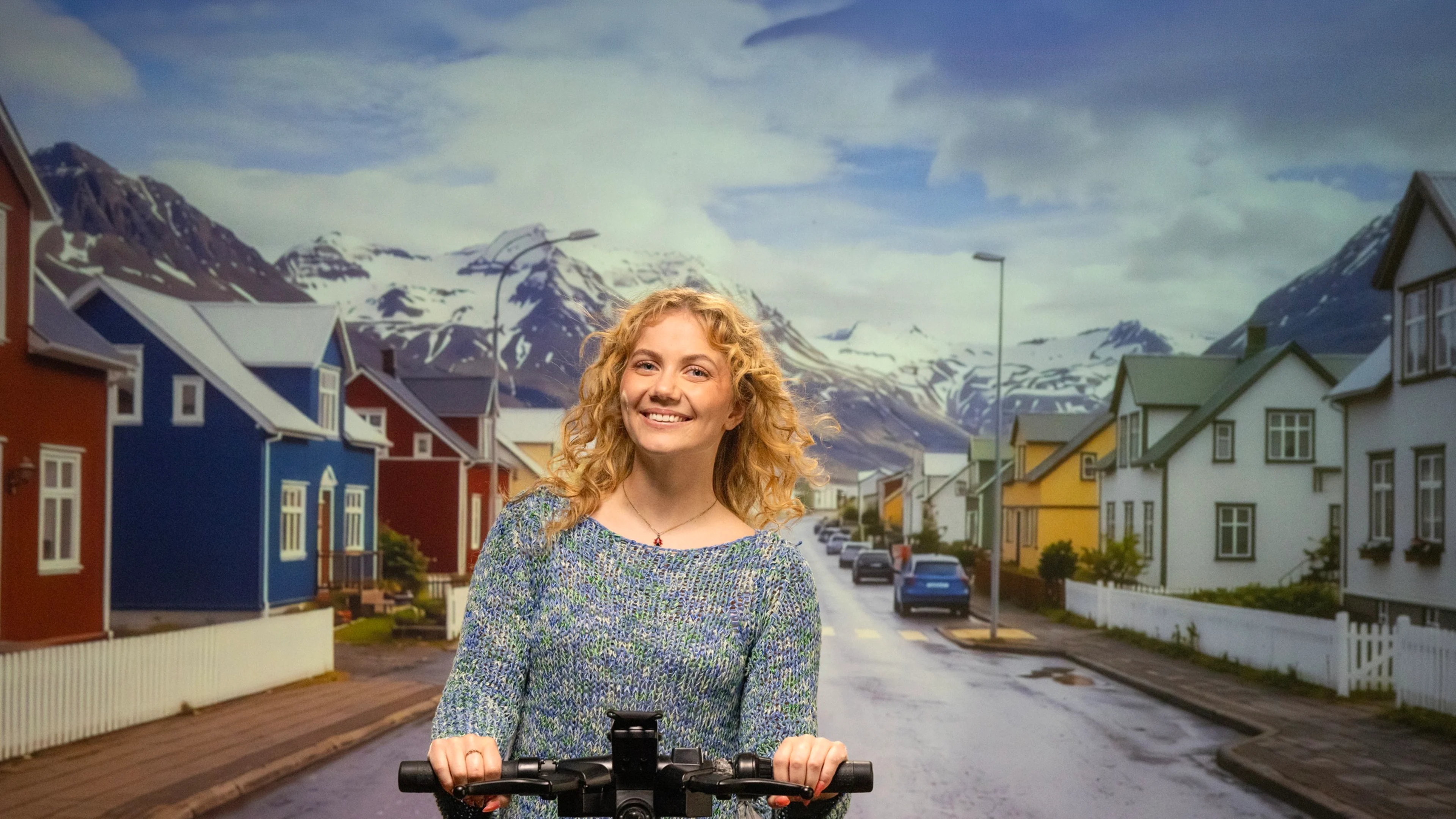 Arion framtíð - kona á hopphjóli á milli fallegra litríkra húsa