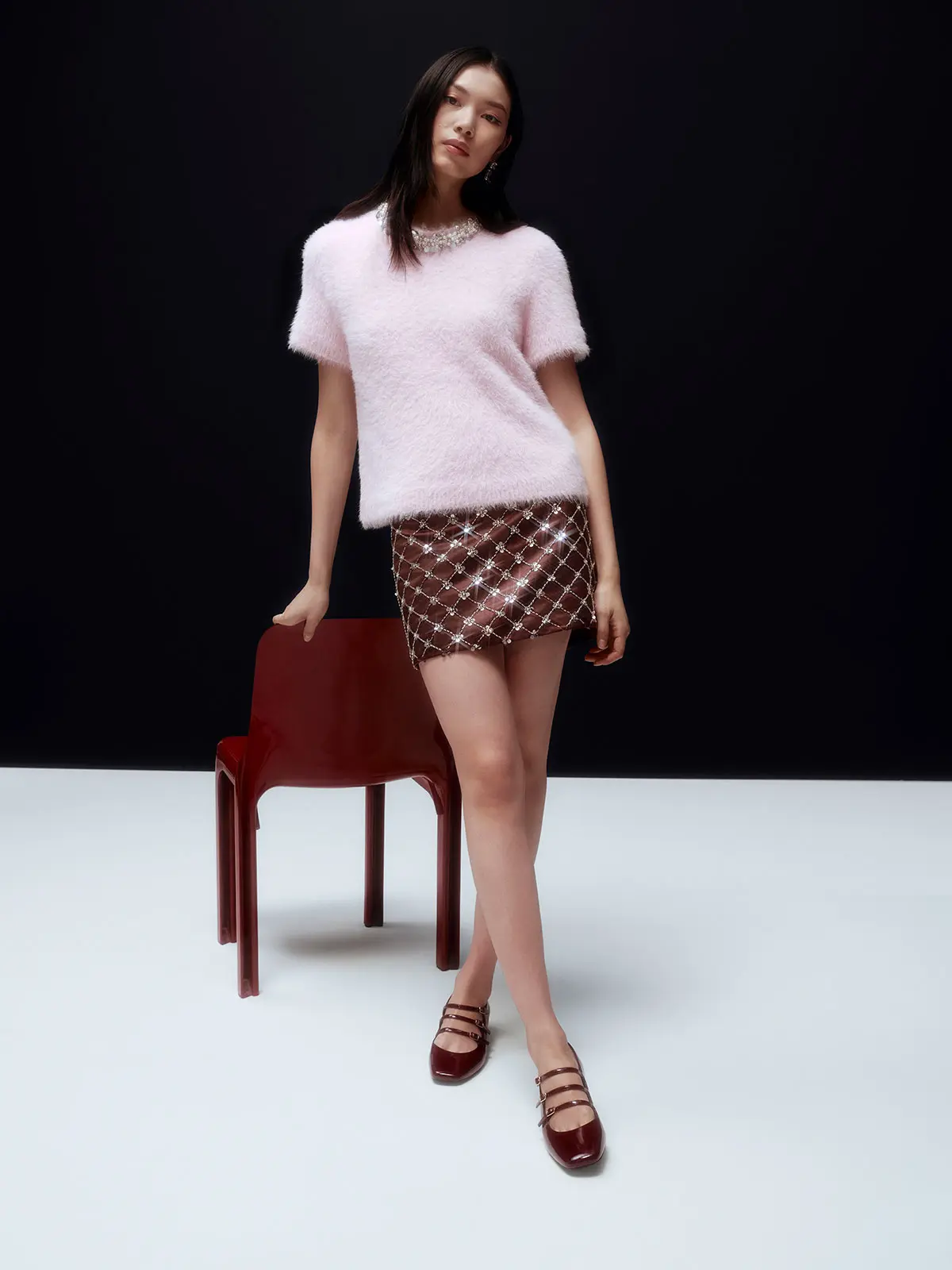 Woman wearing pink short sleeve knit, embellished mini skirt and strappy flats