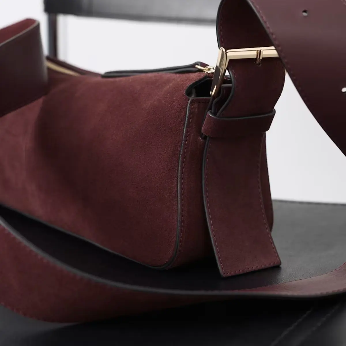 A close up of an Autograph burgundy suede bag