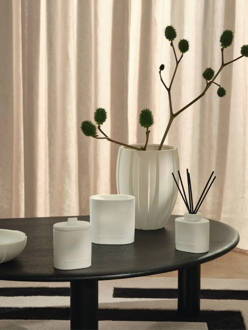 Kelly Hoppen ceramic diffusers and candles sat on a table alongside a cream vase