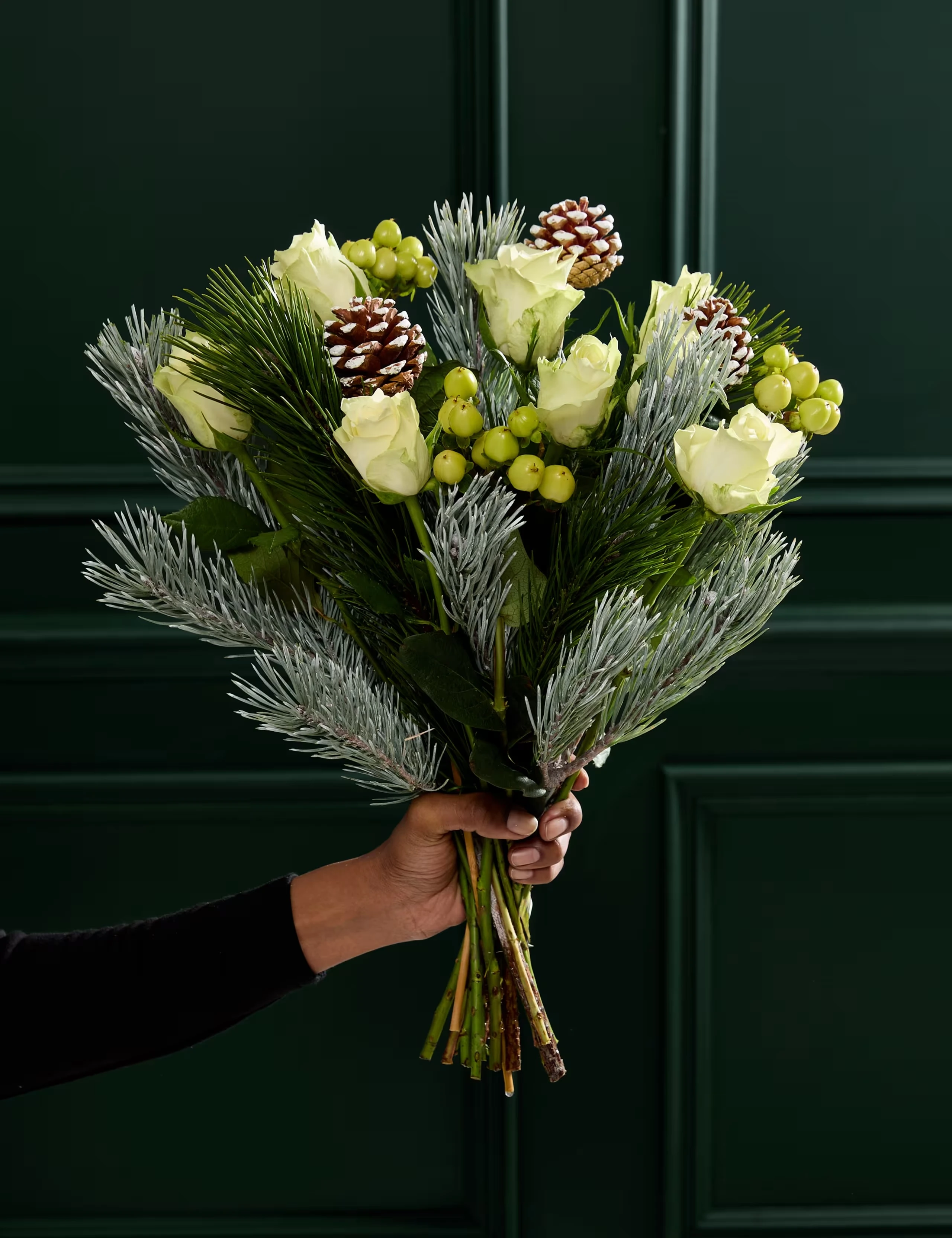 Luxury bouquet of white roses, berries, pine cones and seasonal foliage.
