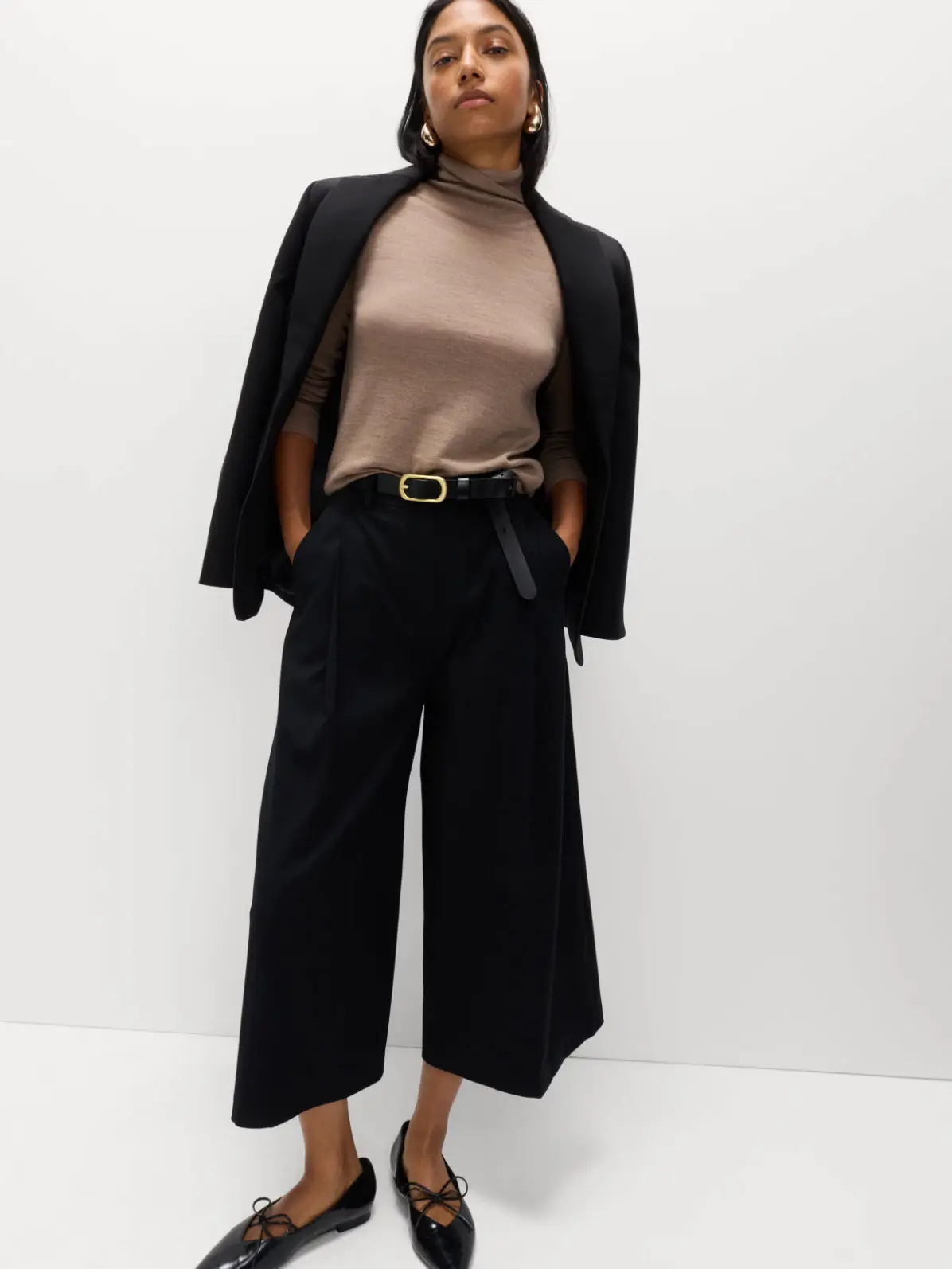 Woman wearing a jumper, culottes, black blazer and pointed flats 