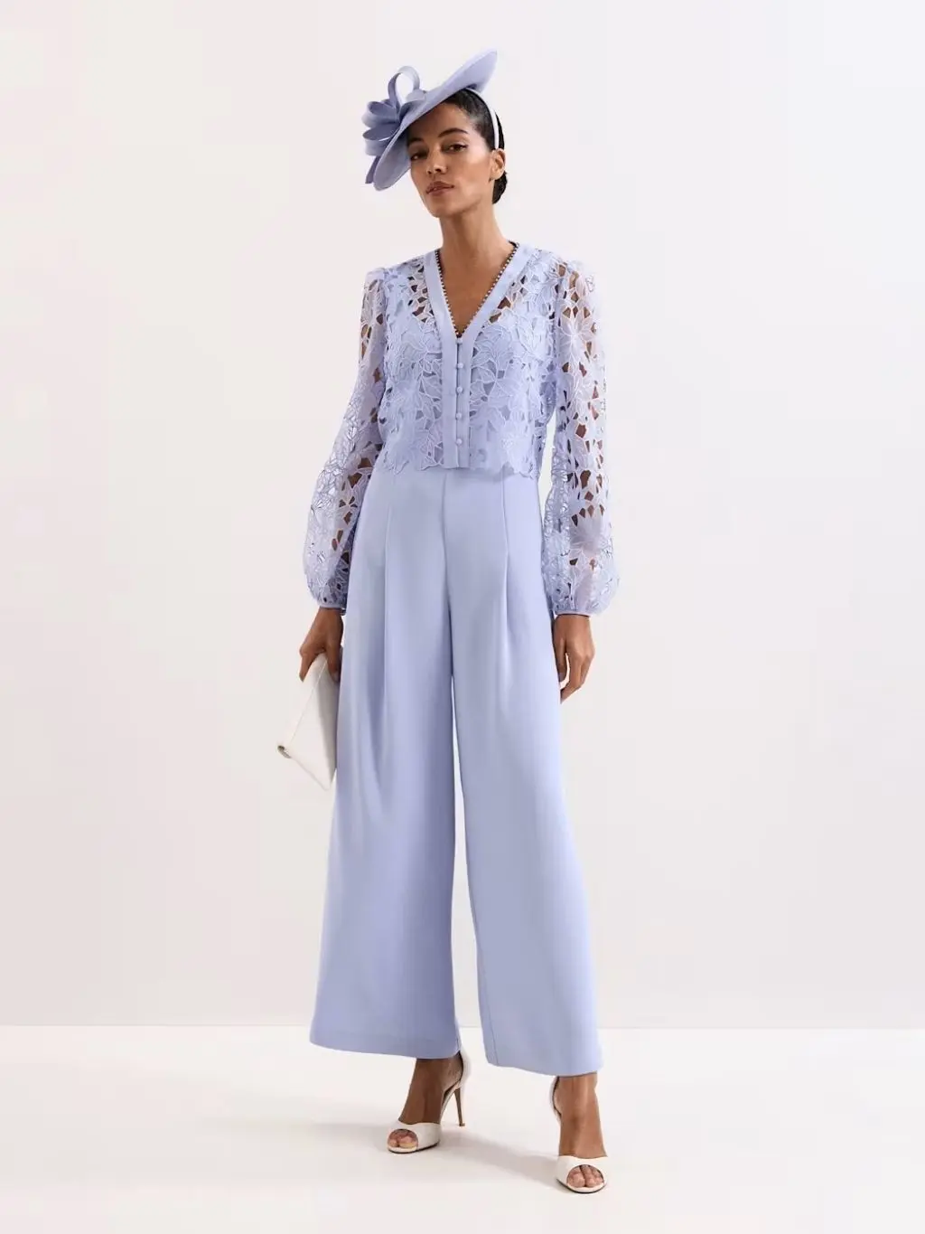 A woman wears a lilac jumpsuit with a fascinator and high heels