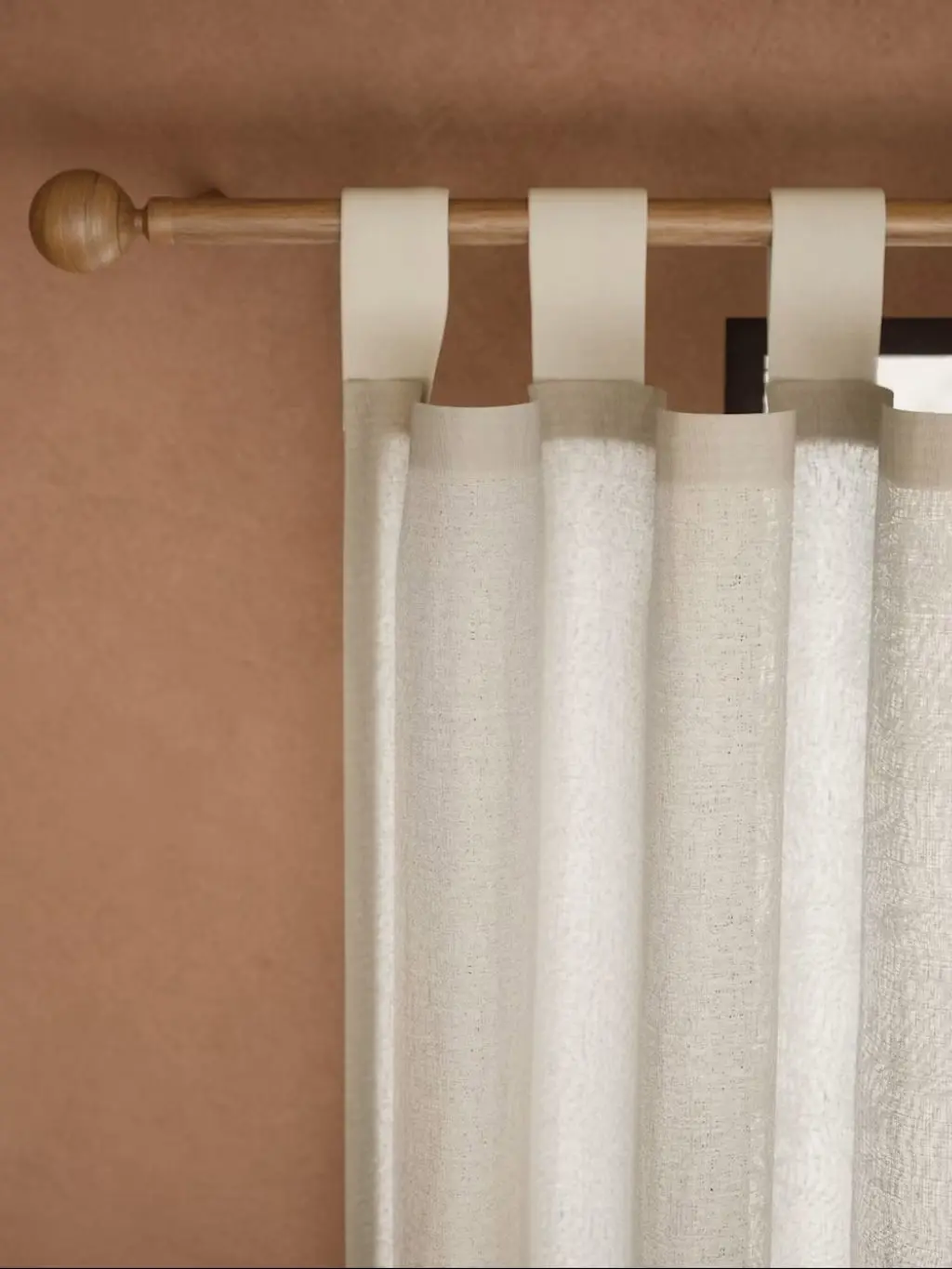 A close up of cream curtains with a tab top