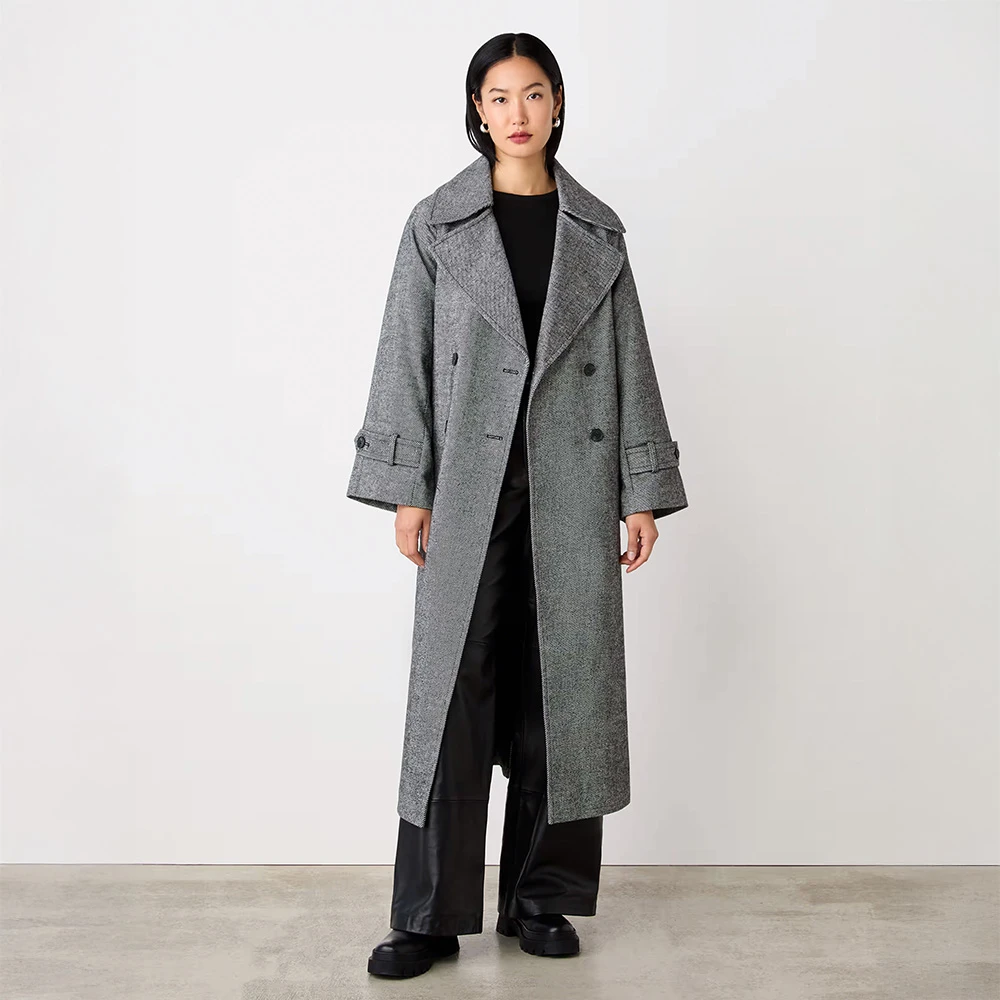 Woman wearing long grey coat, black top, black trousers and black Chelsea boots