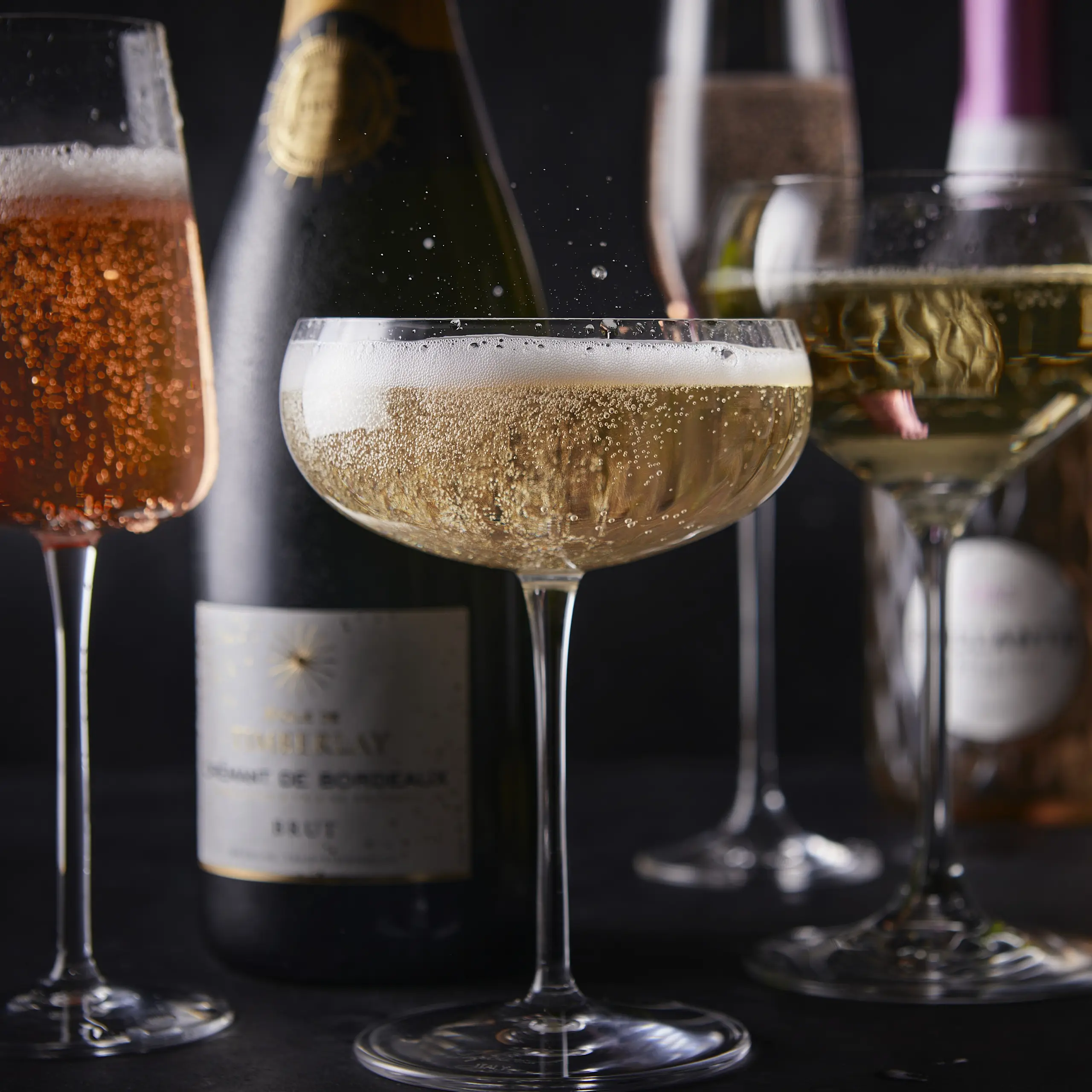 Glass of sparkling wine with bottles in background