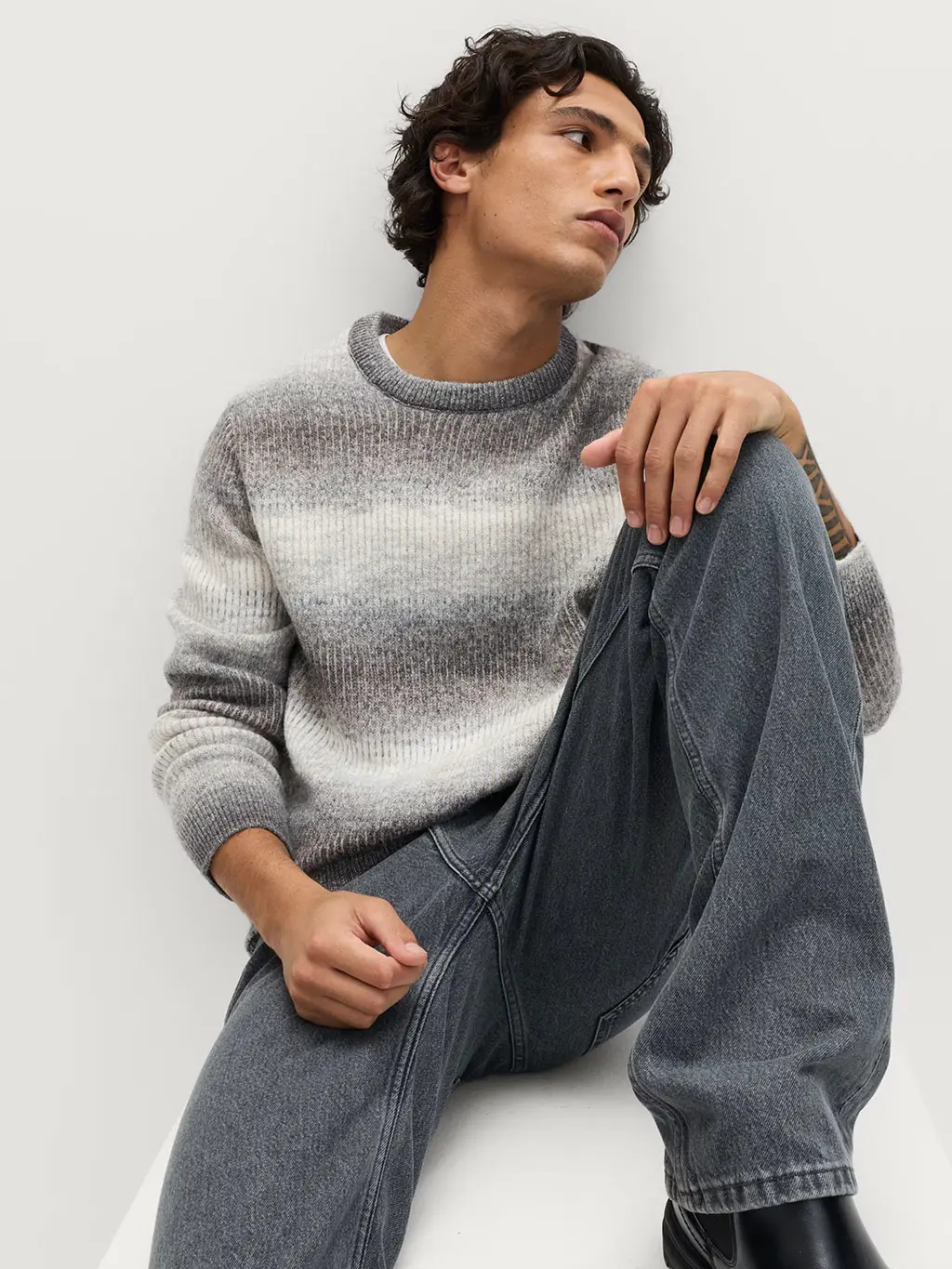 Man wearing grey striped jumper with jeans and black boots