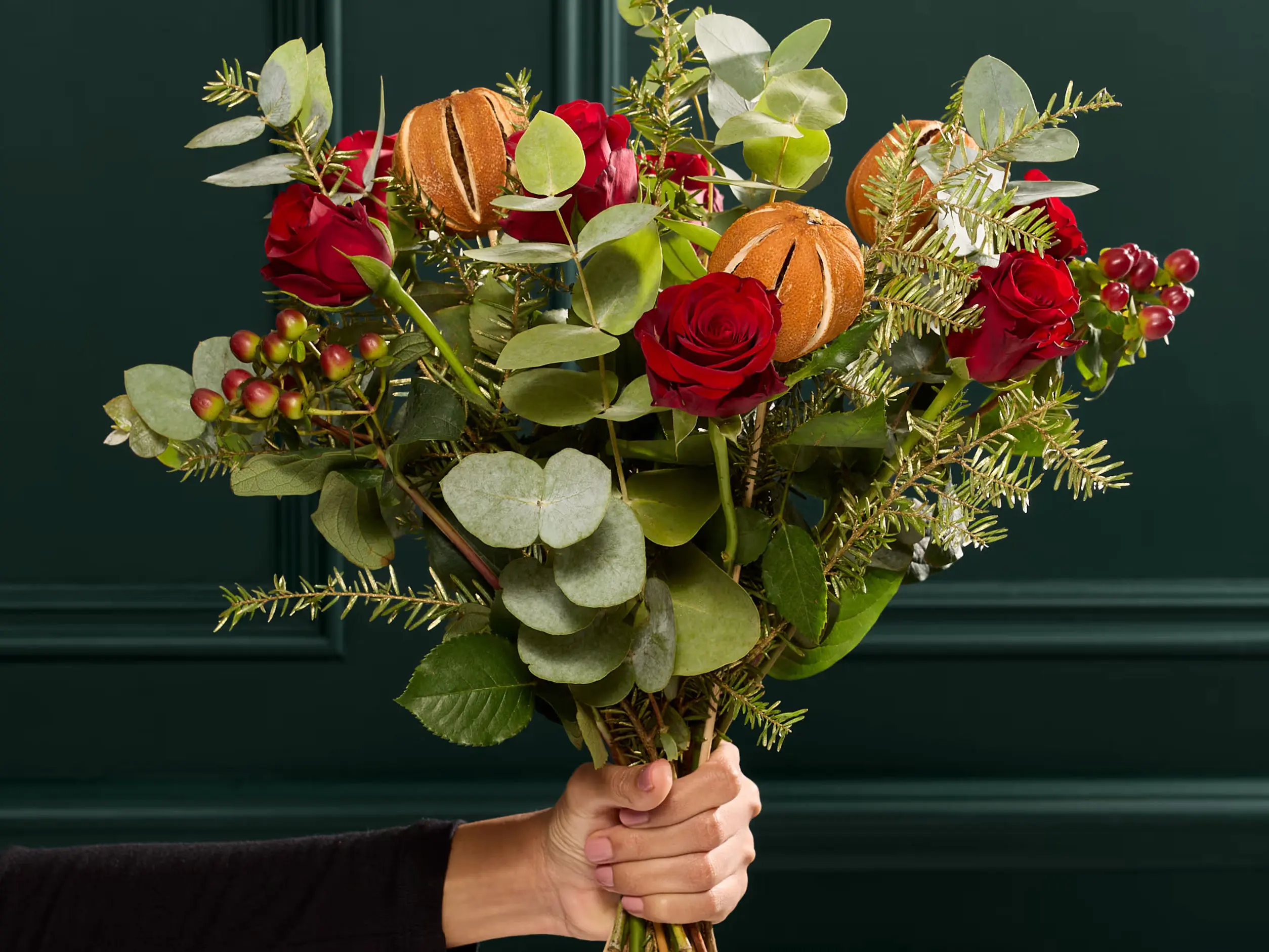 Hand holding a bouquet of Christmas flowers