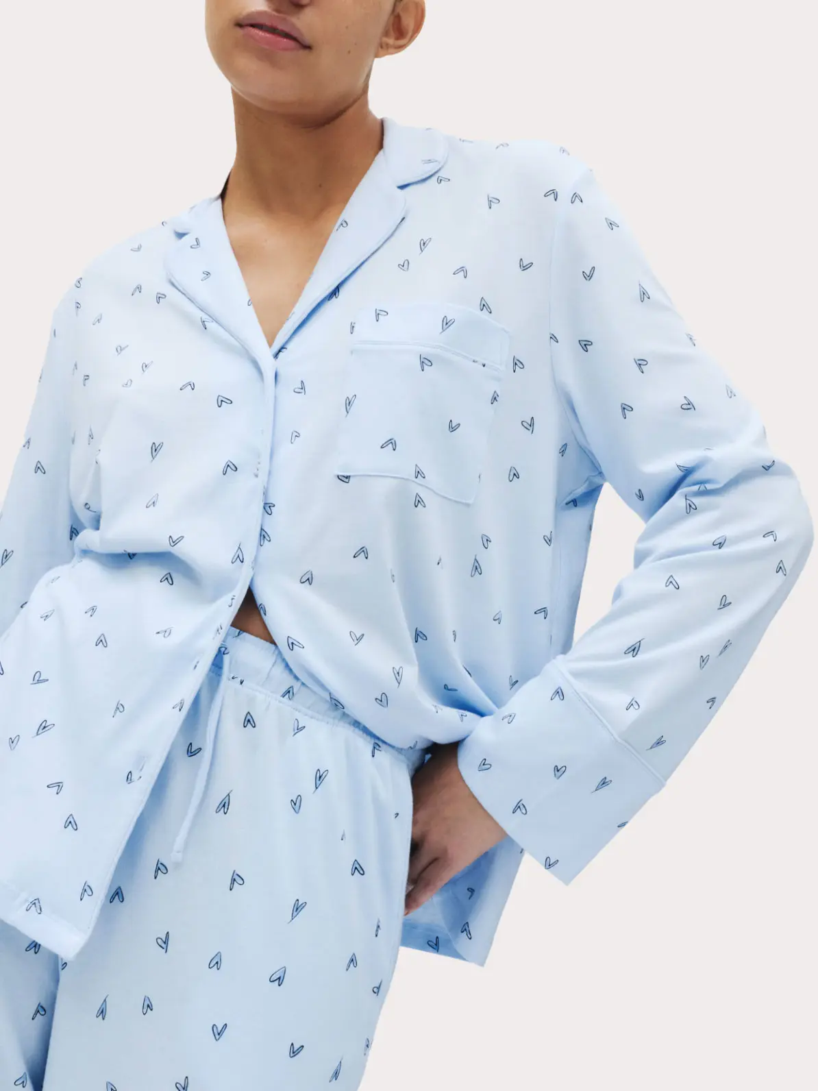 Woman wearing light blue matching pyjama set with heart print 