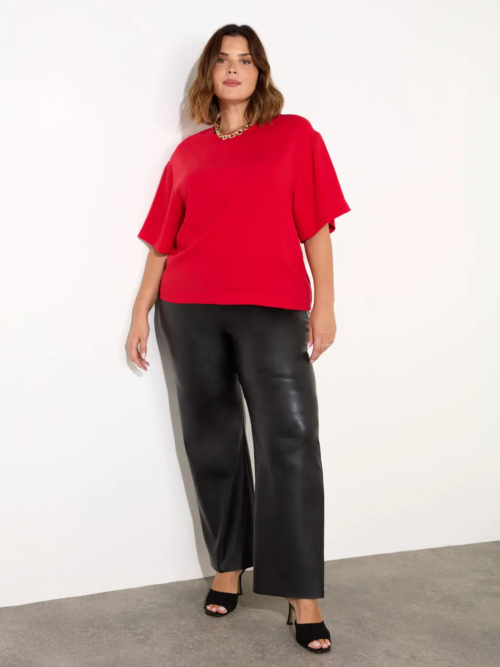 Woman wearing black leather trousers and a red top